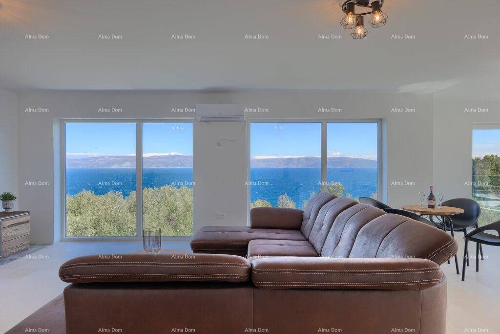 Helles Wohnzimmer mit großer Couch und Panoramafenstern mit Meerblick.