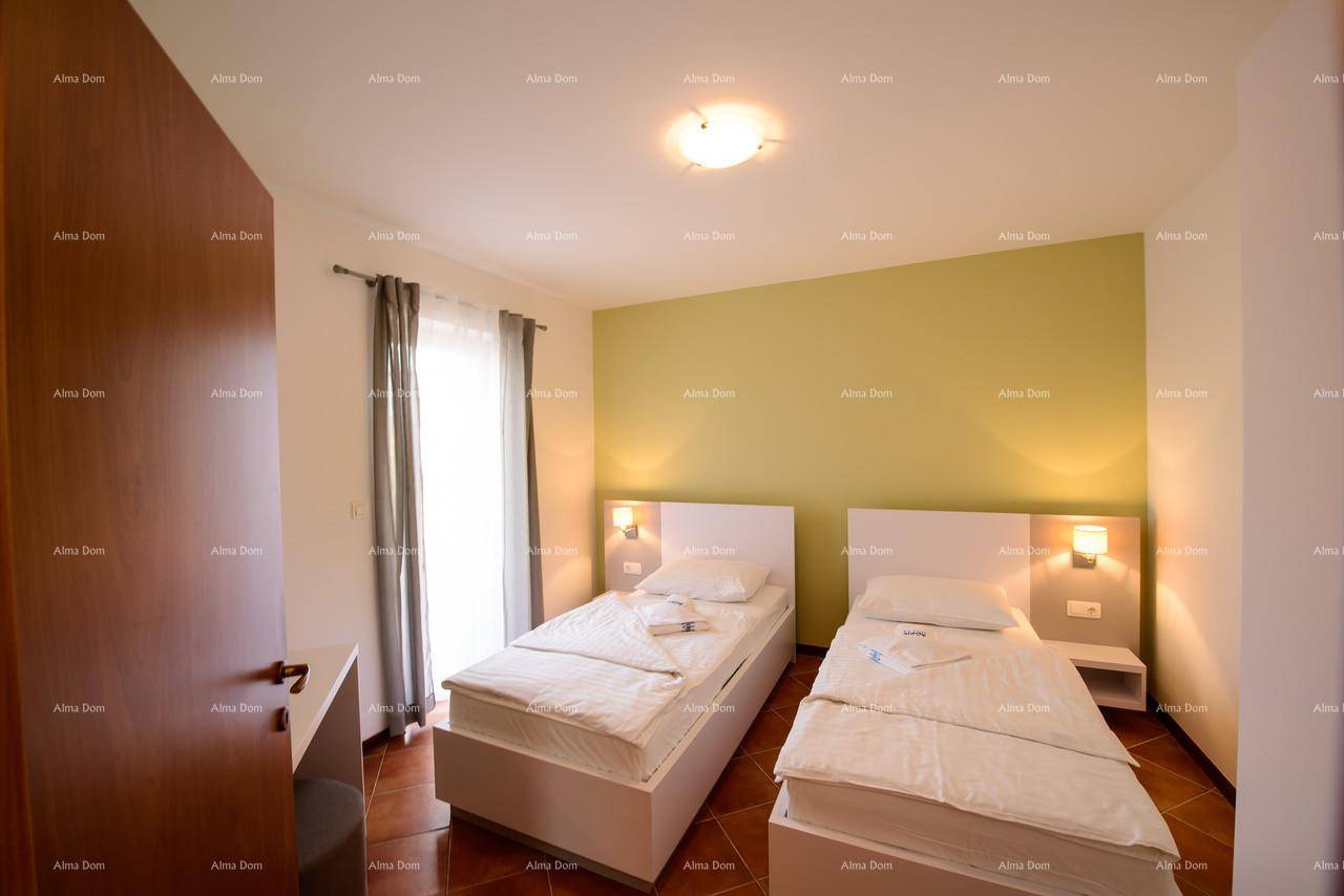 Helles Schlafzimmer mit zwei Einzelbetten, grüner Akzentwand und Balkonzugang.