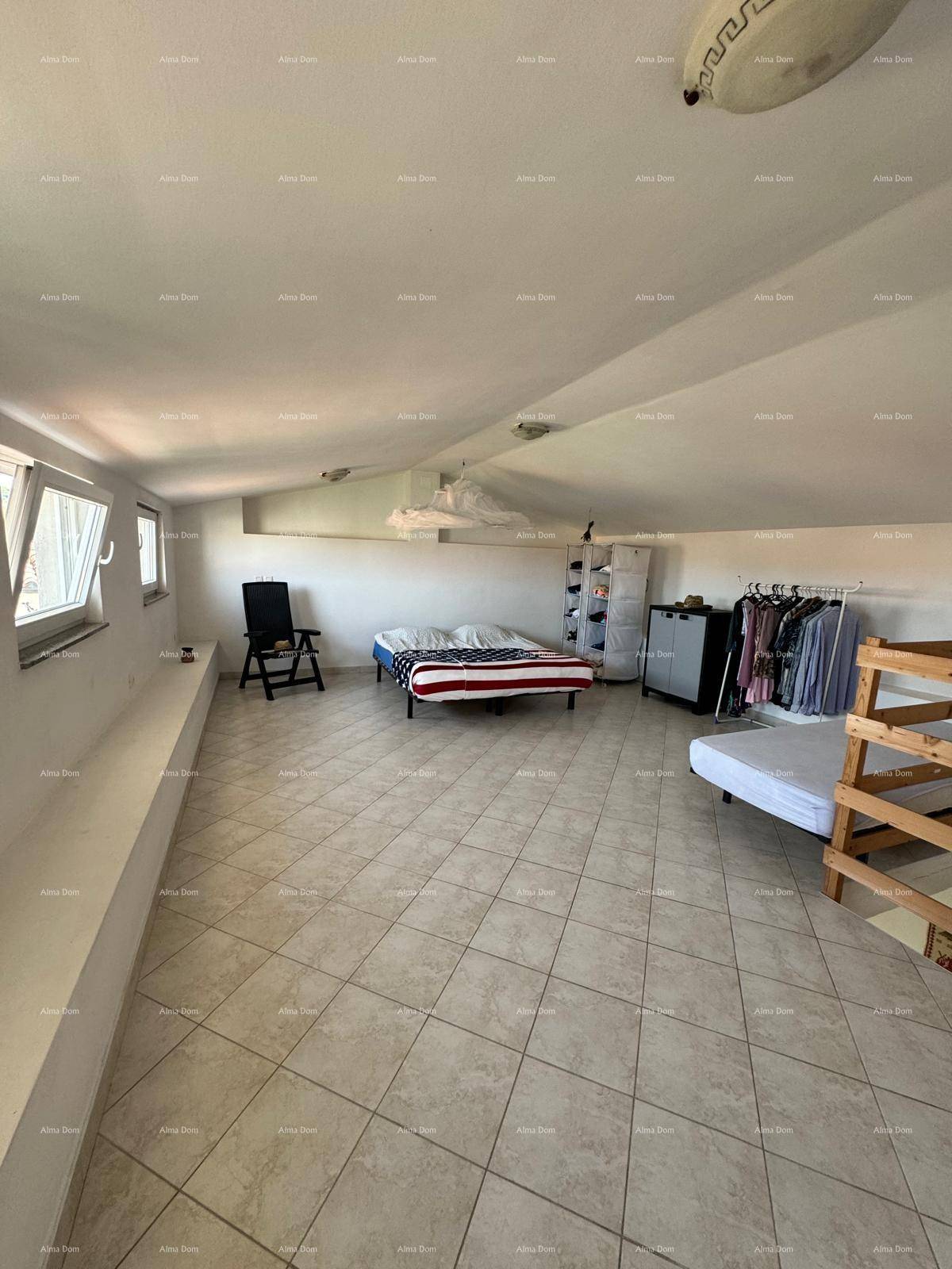 Großes Schlafzimmer im Dachgeschoss mit schrägen Wänden, mehreren Betten und viel Tageslicht.