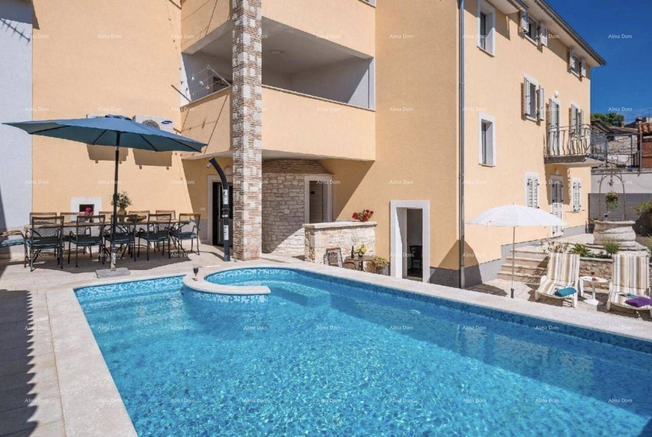 Nahaufnahme des Pools und der Terrasse mit Sonnenschirm und Essbereich neben dem Haus.