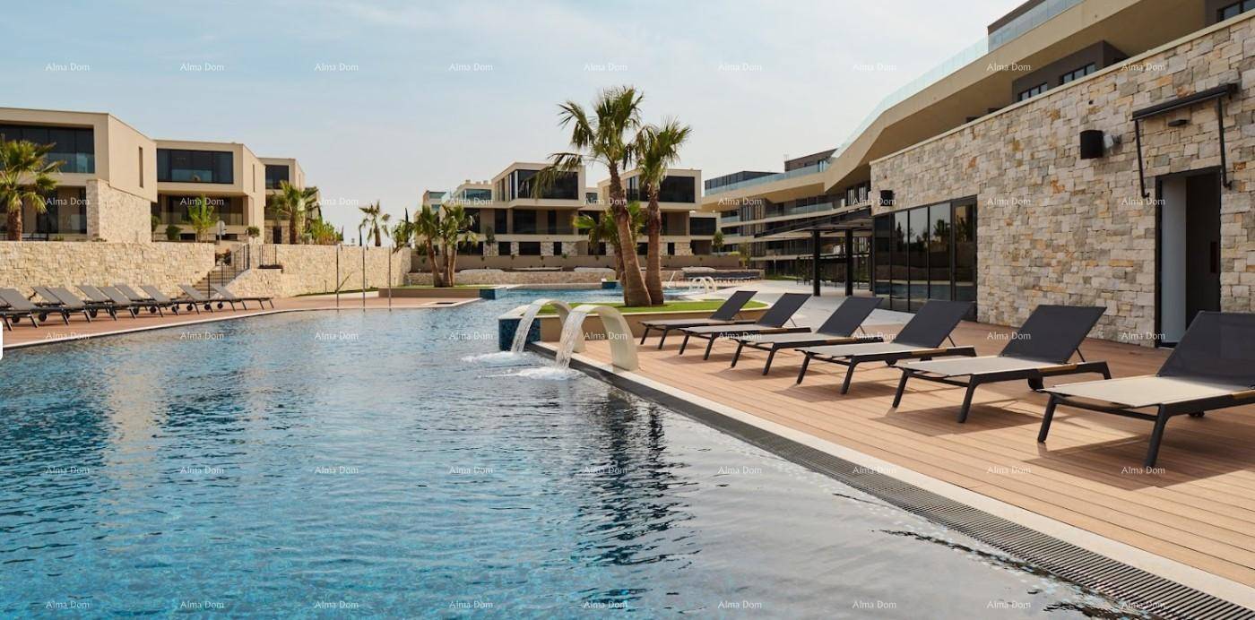 Großer Außenpool mit Wasserspielen, Liegestühlen und moderner Architektur im Hintergrund.