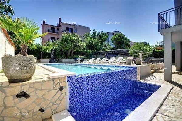 Infinity-Pool mit blauen Mosaikfliesen und angrenzendem gepflasterten Bereich.