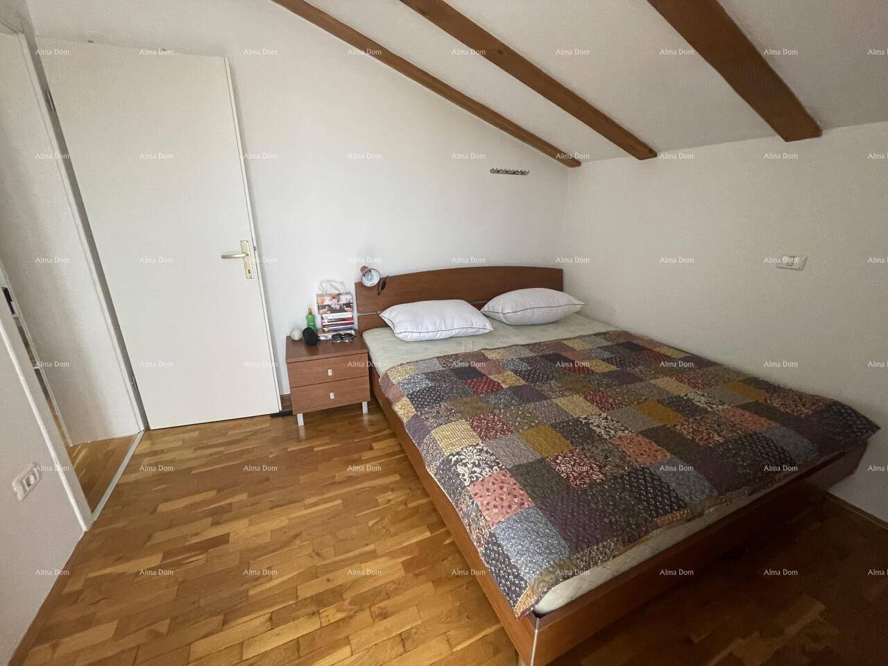 Helles Schlafzimmer mit Holzboden, Dachschräge und einem bequemen Doppelbett, ideal für erholsame Nächte.