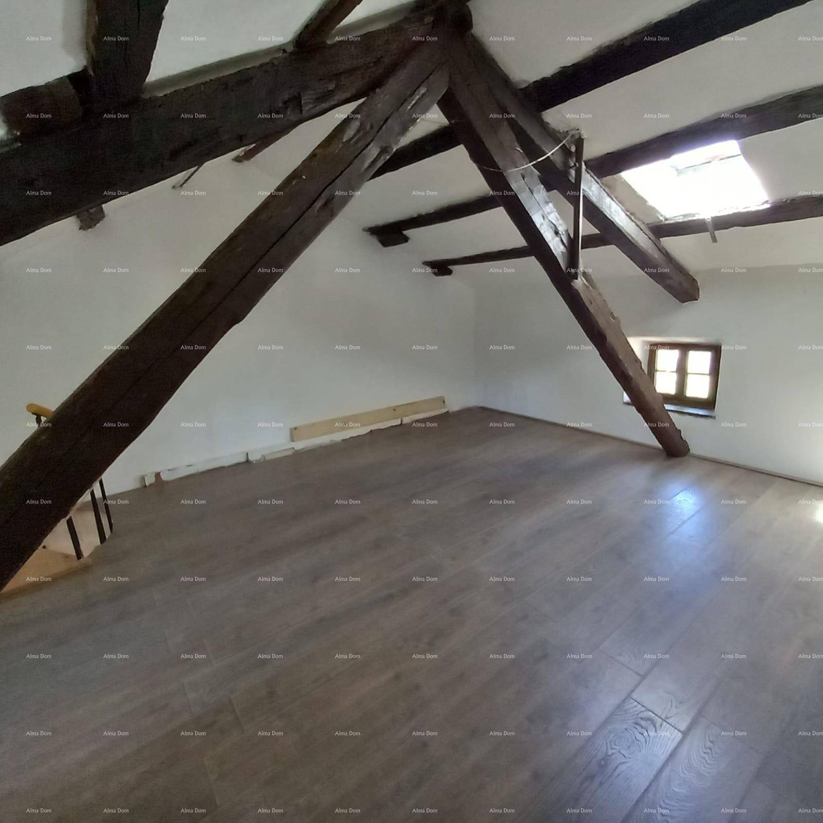 Geräumiger Dachboden mit sichtbaren Holzbalken, schrägen Decken und einem Dachfenster.