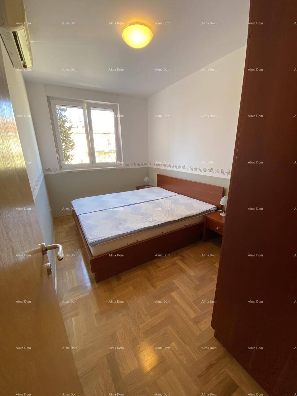 Schlafzimmer mit Doppelbett, Fischgrätparkett und Klimaanlage für angenehme Nächte.