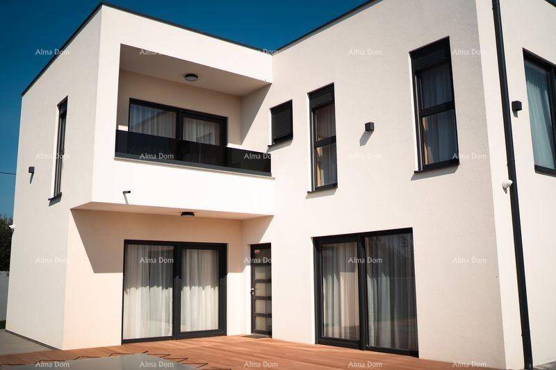 Moderne weiße Hausfassade mit klaren Linien, großen Fenstern und einem kleinen Balkon im Obergeschoss.
