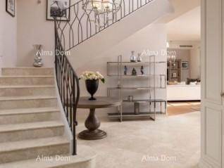 Elegante Treppe mit schmiedeeisernem Geländer und dekorativem Beistelltisch im hellen Flur.