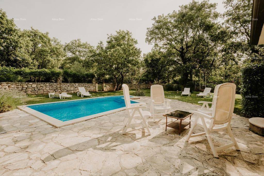 Außenpoolbereich mit gepflasterter Terrasse, Liegestühlen und umgebendem Grün, perfekt zum Sonnenbaden.