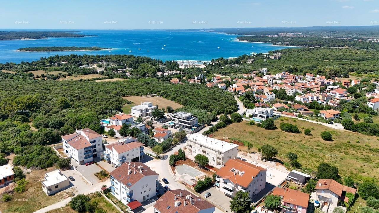Luftaufnahme einer Wohngegend mit mediterraner Vegetation und dem glitzernden Meer im Hintergrund.