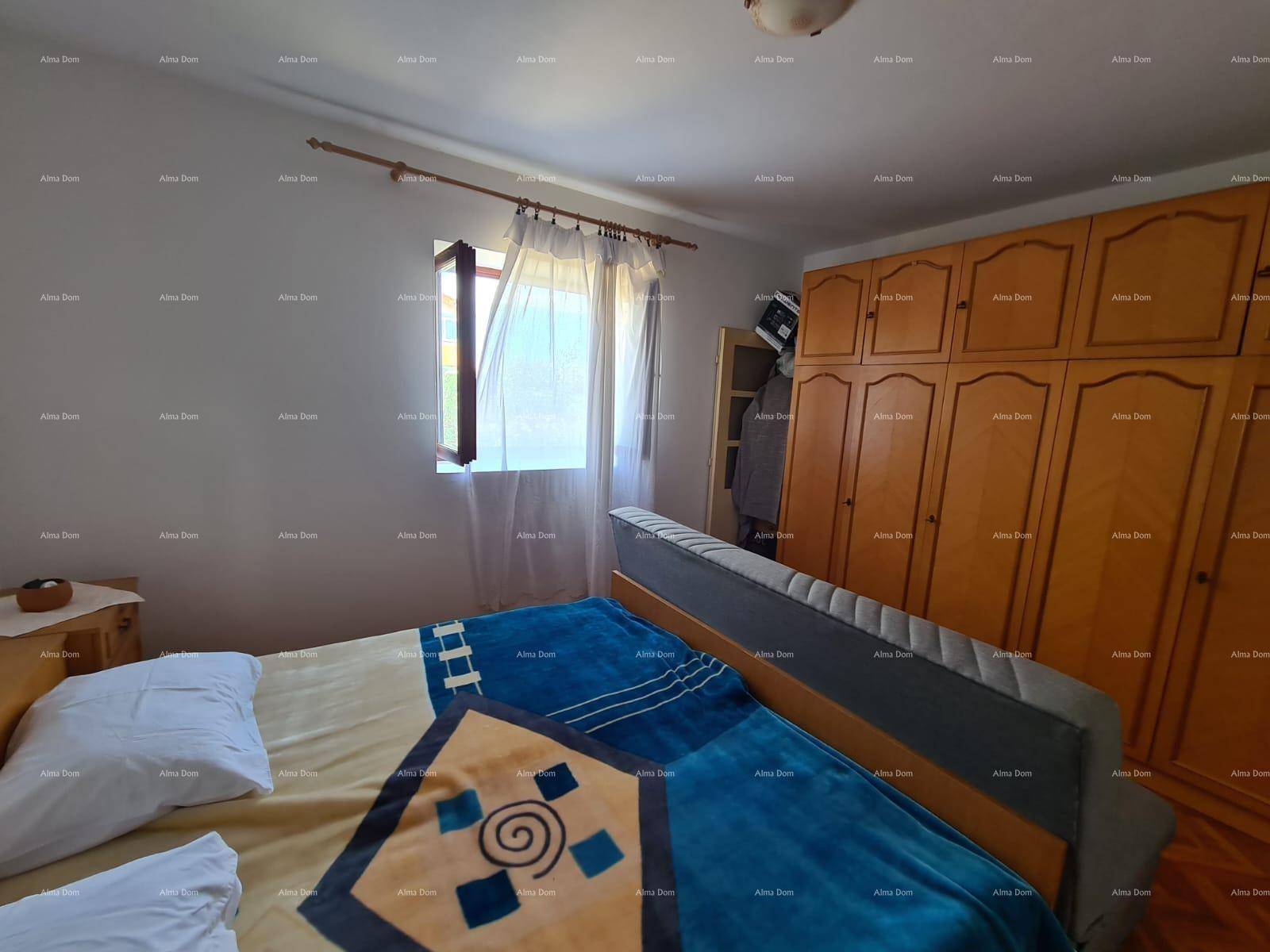 Schlafzimmer mit Holzboden, einem Bett und einem großen Holzschrank für Stauraum.