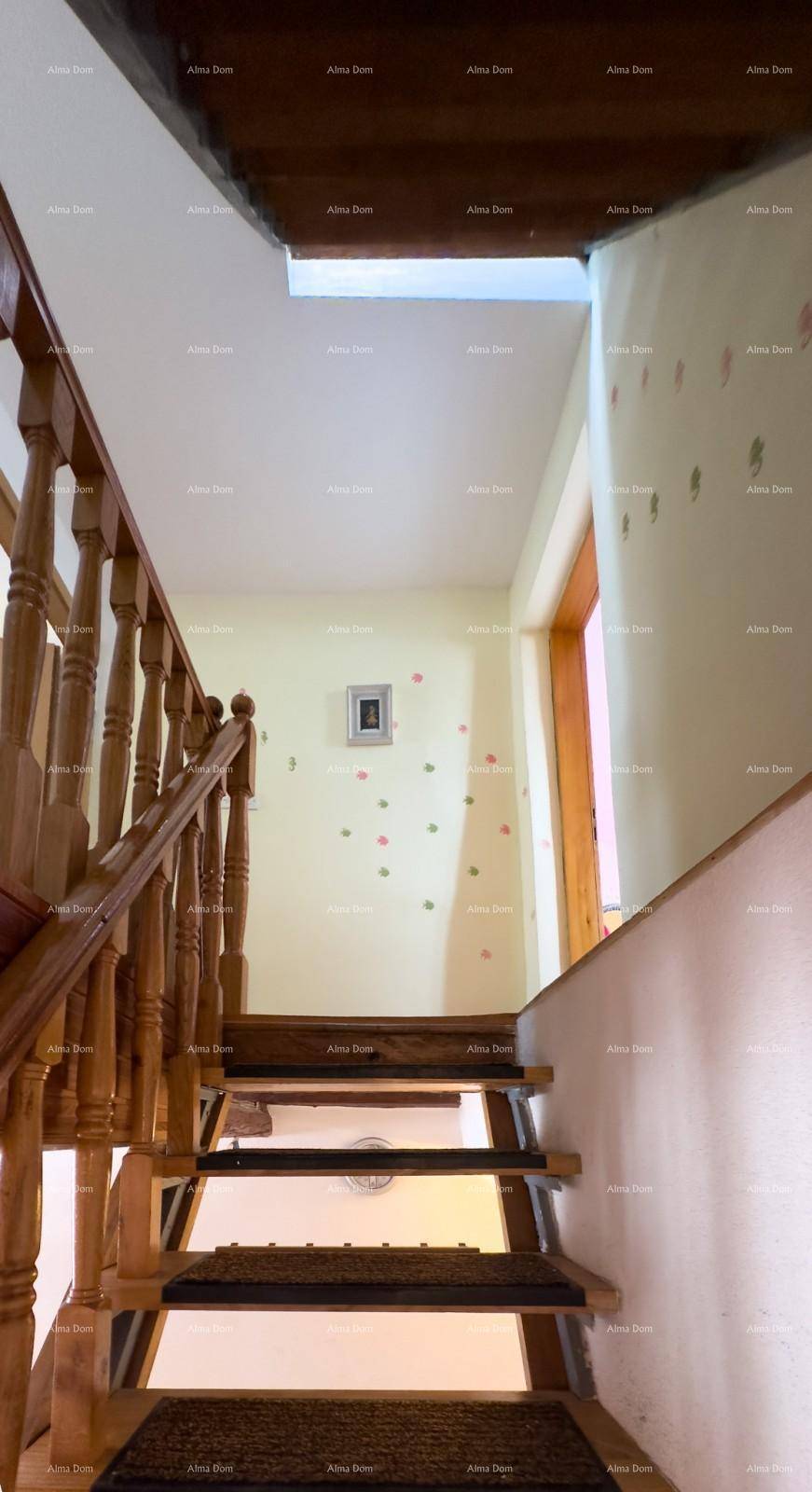 Holztreppe mit Geländer führt in die obere Etage, umgeben von hellen Wänden.