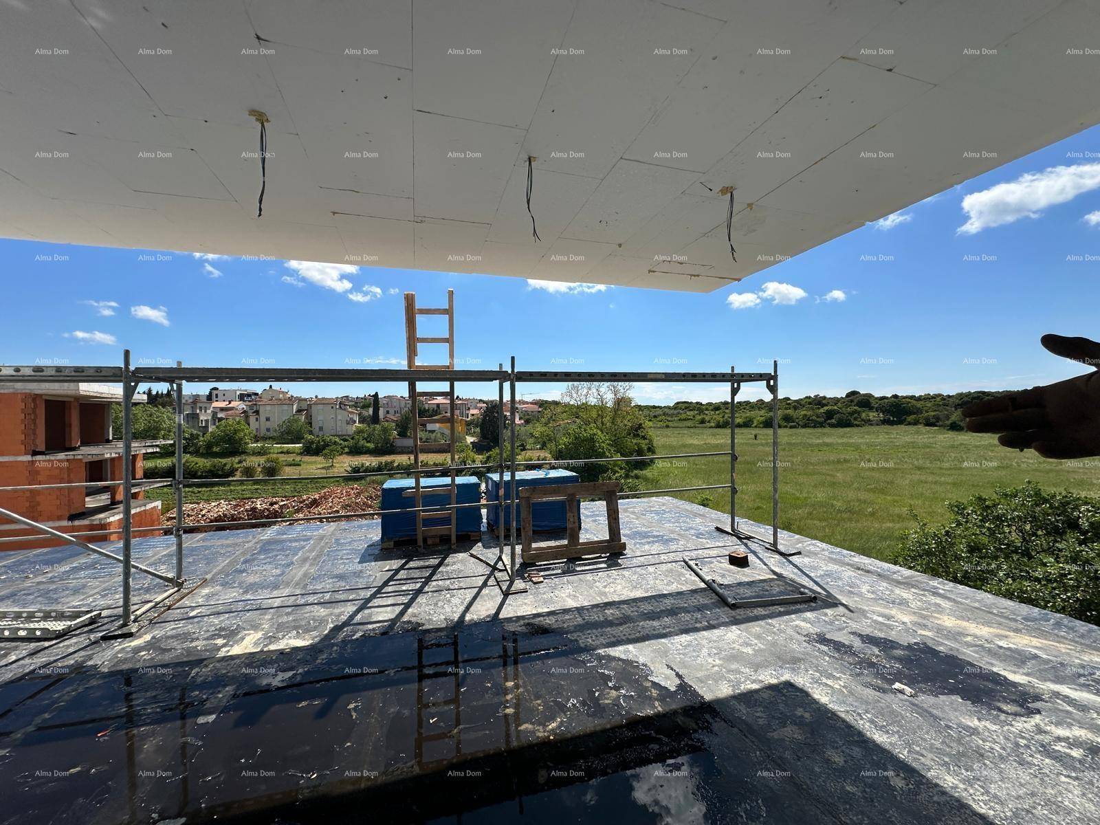 Blick von einer Baustelle auf die umliegende grüne Landschaft und weitere Gebäude.