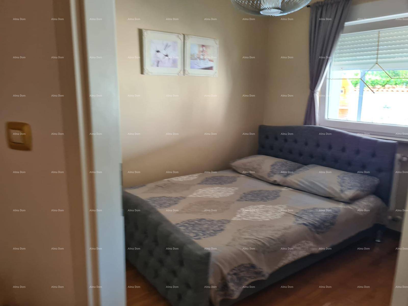 Komfortables Schlafzimmer mit gepolstertem Bett, Holzboden und Fenster mit Blick ins Grüne.