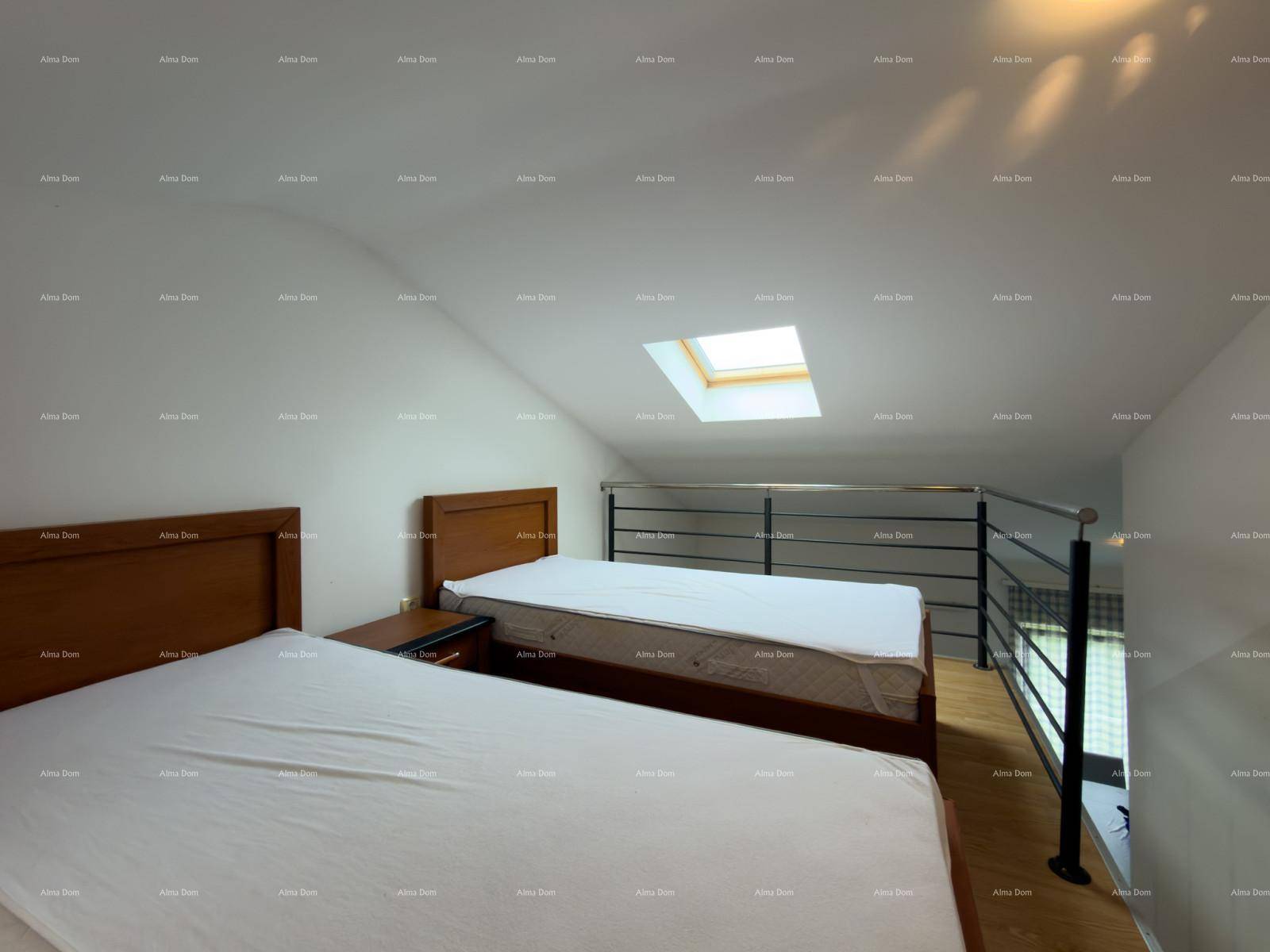 Dachgeschoss-Schlafzimmer mit Betten und einem Geländer, das den Blick nach unten freigibt.