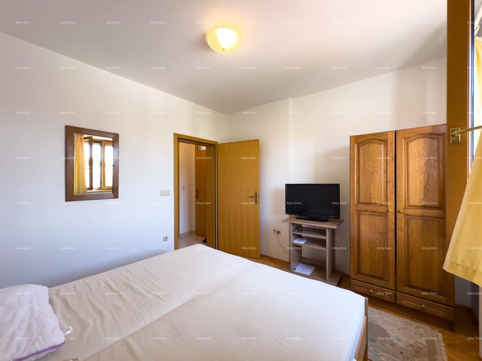 Schlafzimmer mit Doppelbett und Holzschrank, Tür führt zu einem angrenzenden Raum.