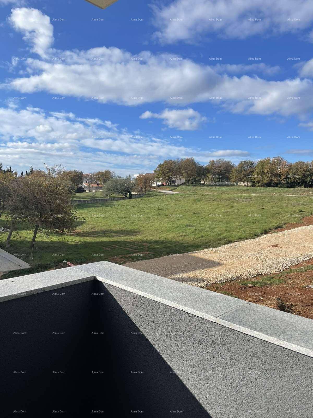 Weitläufiger Blick von einem Balkon über eine grüne Wiese unter blauem Himmel.
