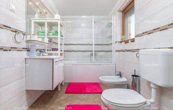 Helles Badezimmer mit Badewanne, Toilette, Bidet und einem einzelnen Waschbecken mit Spiegelschrank.