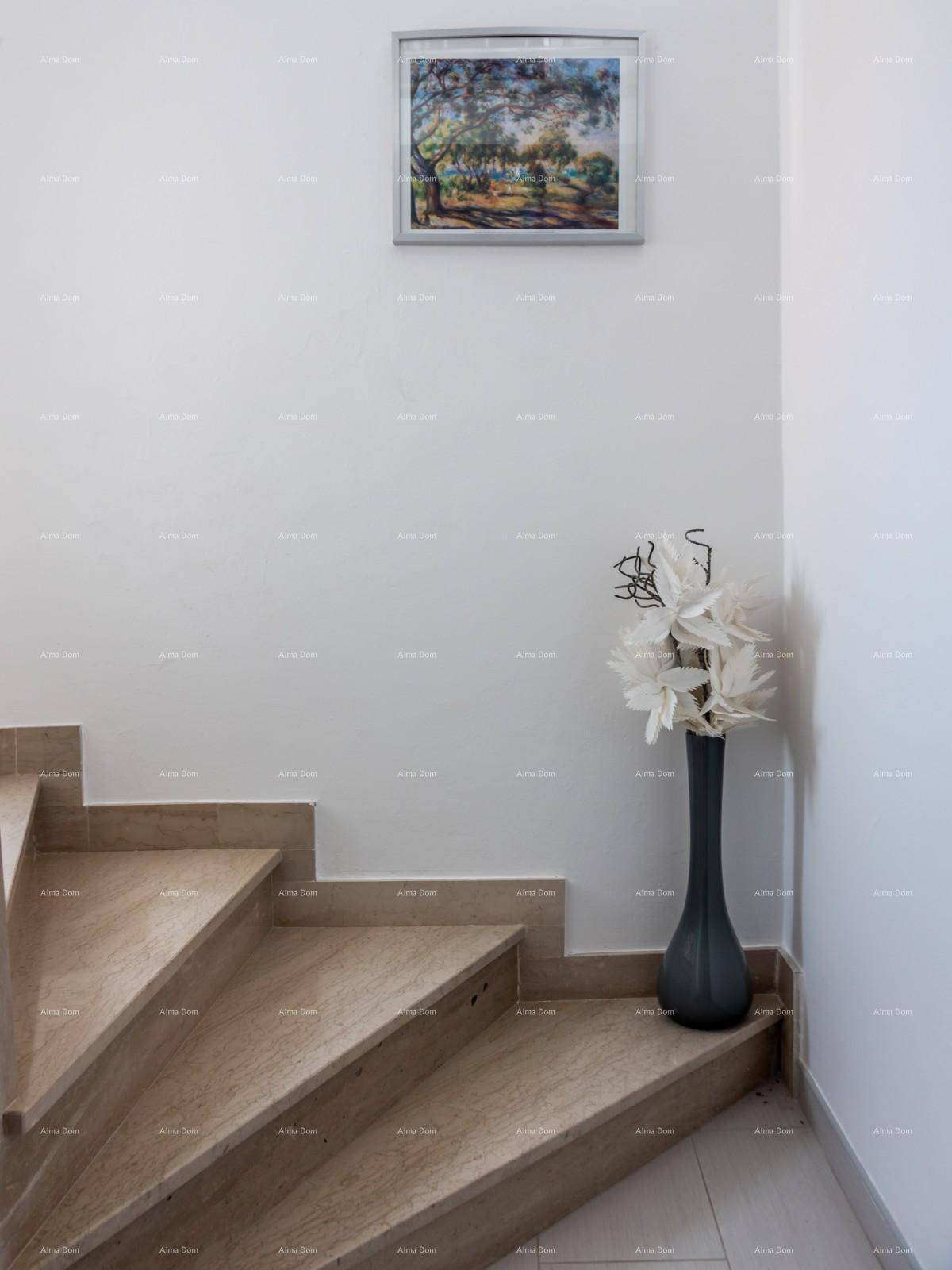Treppenhaus mit Steinstufen, weiß gestrichenen Wänden und dekorativer Kunst.