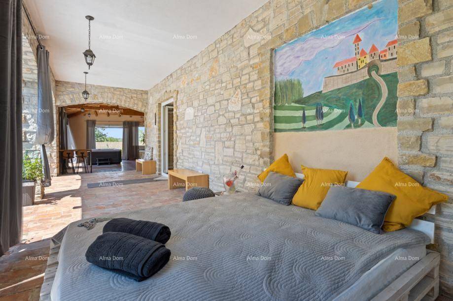 Geräumiges Schlafzimmer mit Steinwand, Holzbalkendecke und Zugang zur Terrasse.