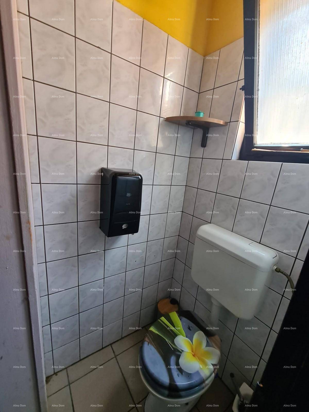 Damentoilette mit weißen Fliesen, einem Fenster und einer Toilette mit dekorativem Deckel.