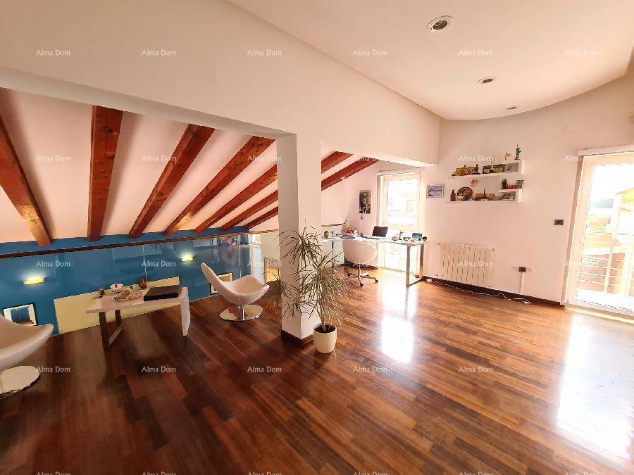 Offener Wohnbereich im Obergeschoss mit Holzboden, hohen Decken und Zugang zu einem Balkon.