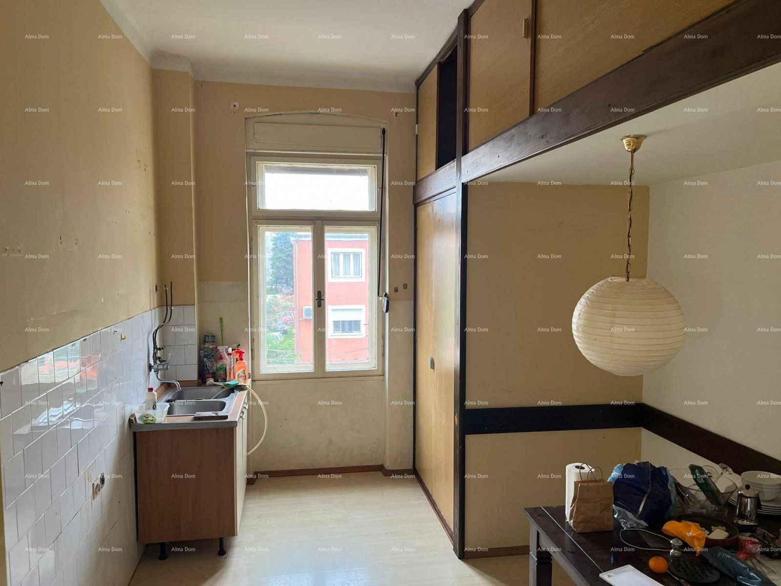 Küche mit Spülbecken, gefliestem Bereich und Holzschränken, ergänzt durch einen Essbereich mit Hängelampe.