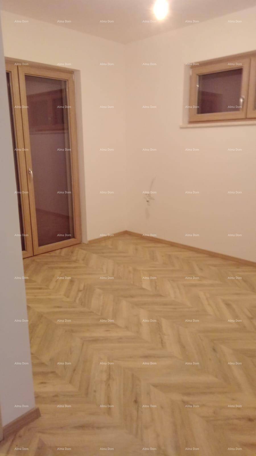 Leeres Zimmer mit hellem Fischgrät-Laminatboden und Zugang zum Außenbereich.