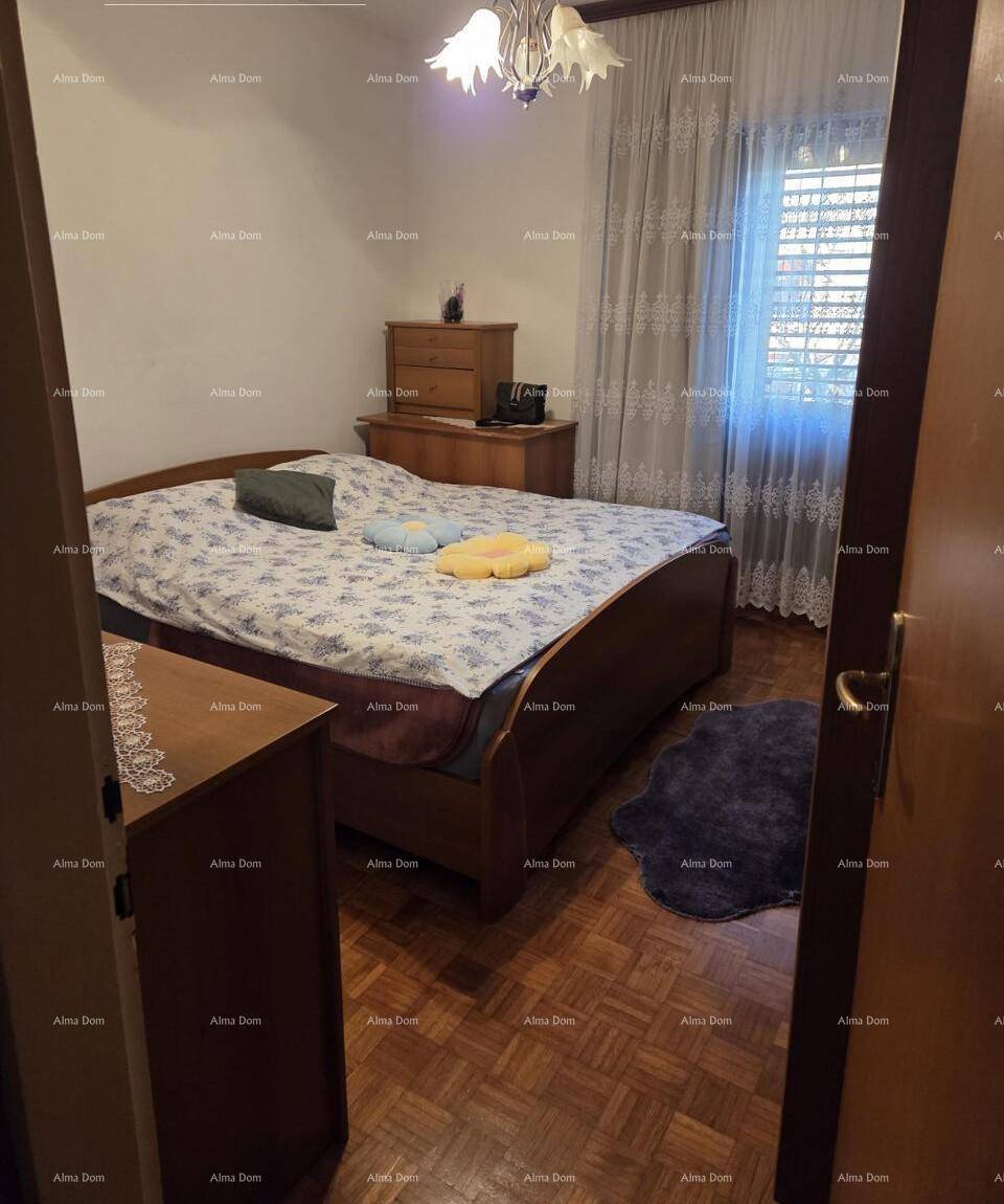 Schlafzimmer mit Doppelbett, Holzkommode und Parkettboden, hell durch das Fenster.