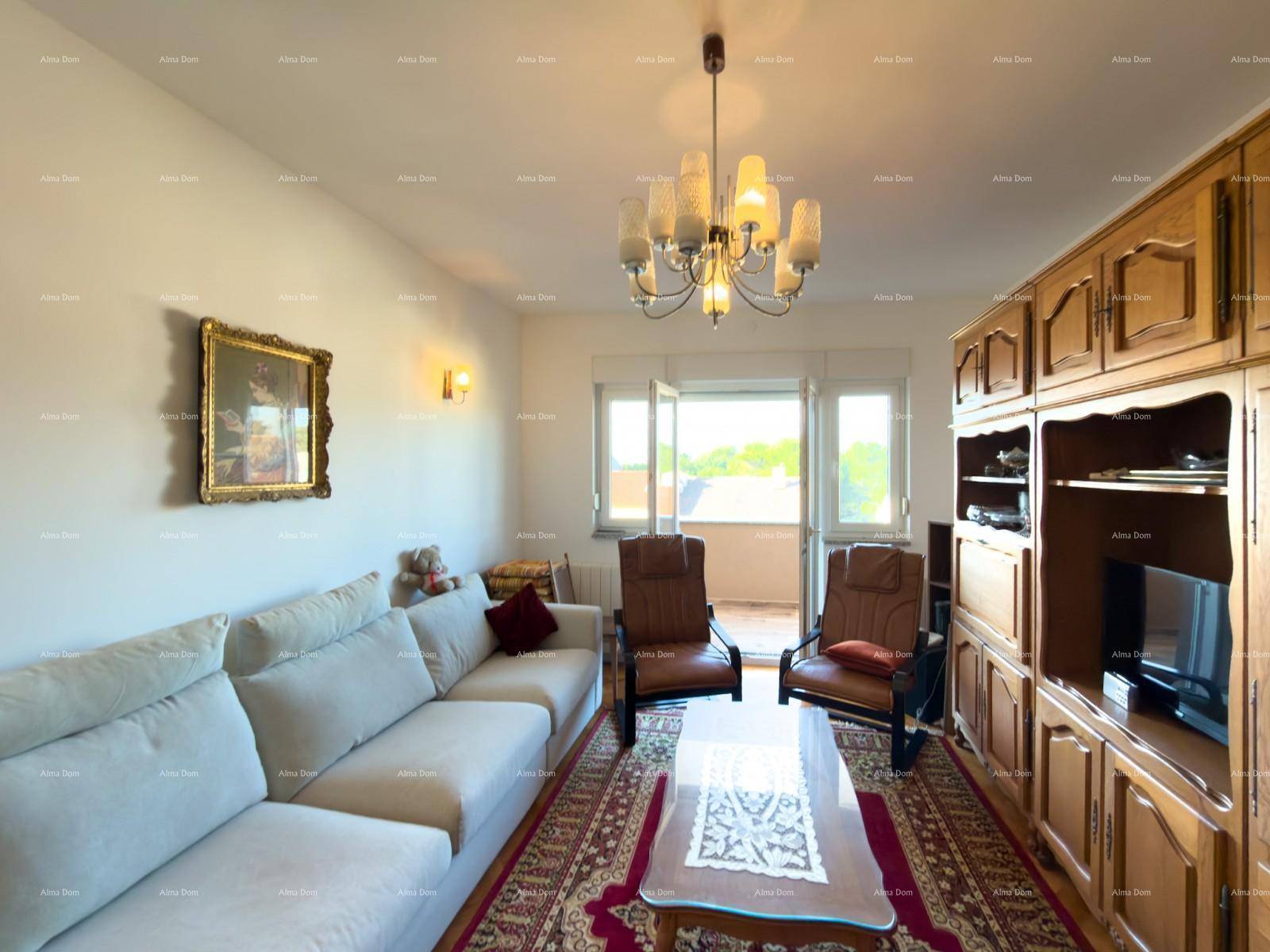 Gemütliches Wohnzimmer mit traditionellem Holzschrank, beigem Sofa und Blick auf den Balkon.