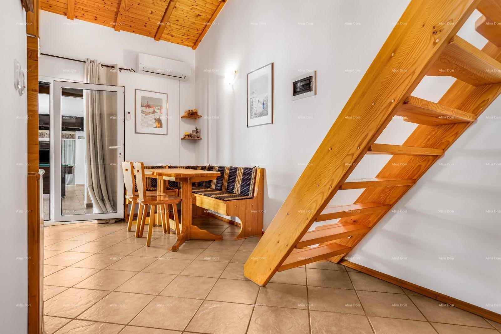 Heller Essbereich mit Holztreppe, Esstisch und Zugang zu einem Außenbereich.