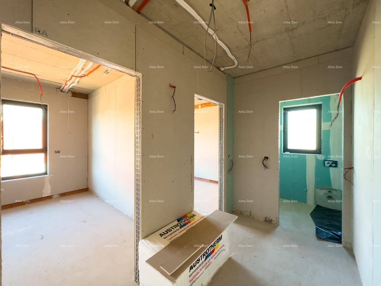 Flur im Rohbau mit Zugang zu mehreren Räumen, darunter ein Badezimmer mit blauen Trockenbauwänden.