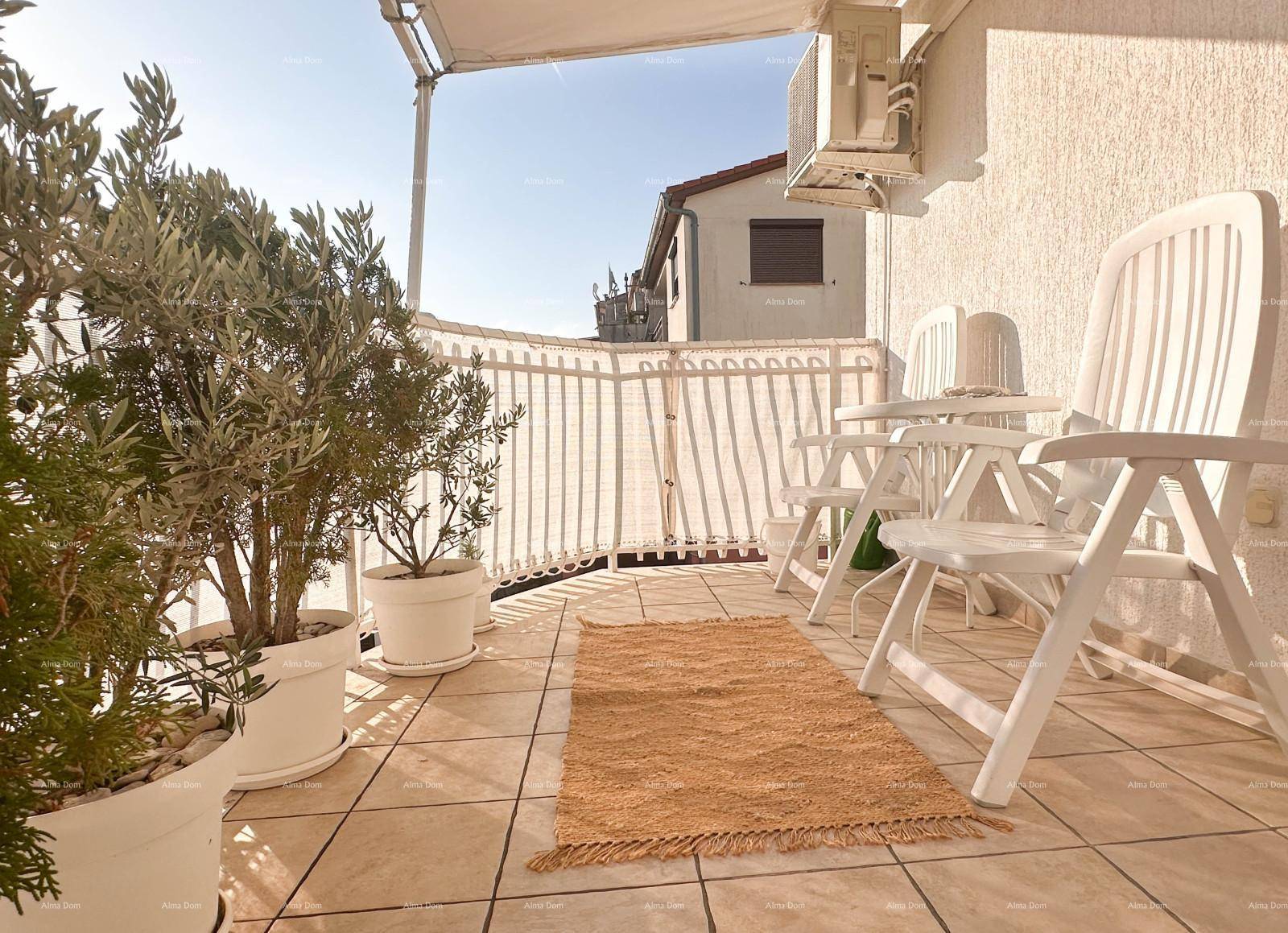 Heller Balkon mit Fliesenboden, Pflanzen und Gartenmöbeln unter einem Sonnenschutz.