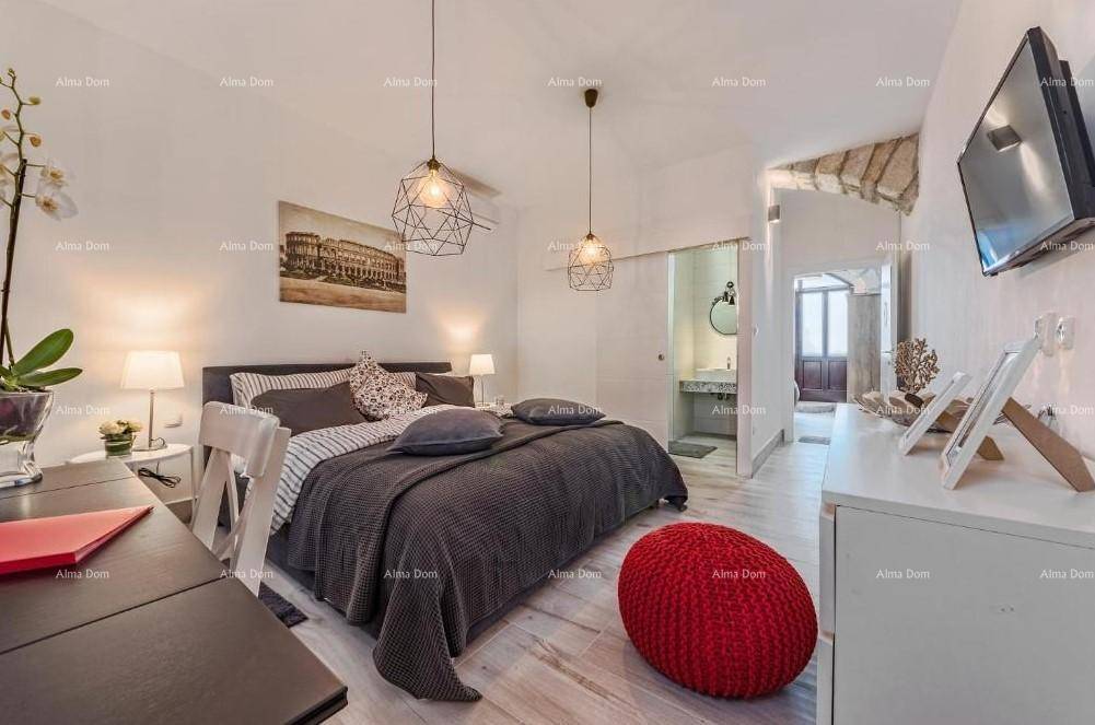 Schlafzimmer mit modernem Bett, Holzboden und Zugang zu einem Badezimmer durch eine Schiebetür.