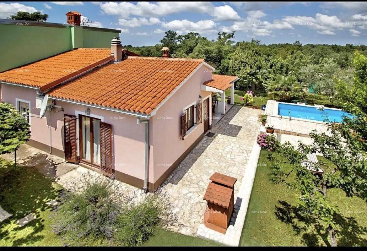 Seitenansicht des Hauses mit gepflastertem Bereich, Garten und Blick auf den Swimmingpool.