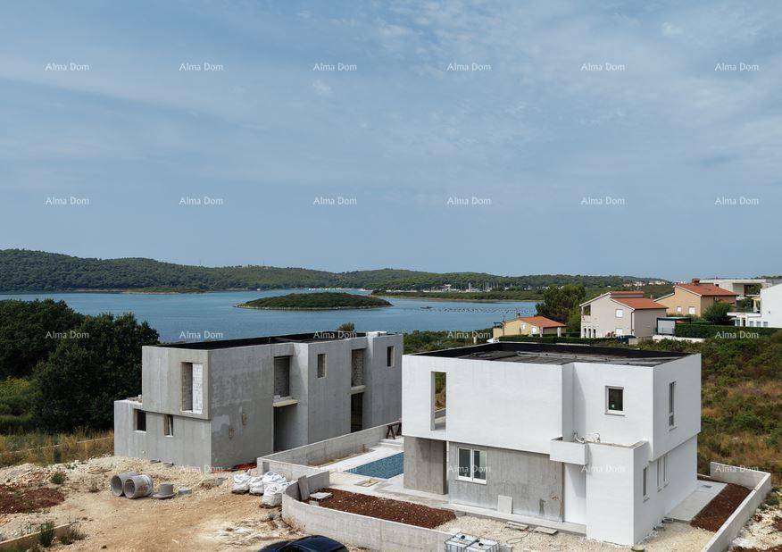 Zwei moderne Villen im Bau mit Blick auf das Meer und die umliegende grüne Landschaft.