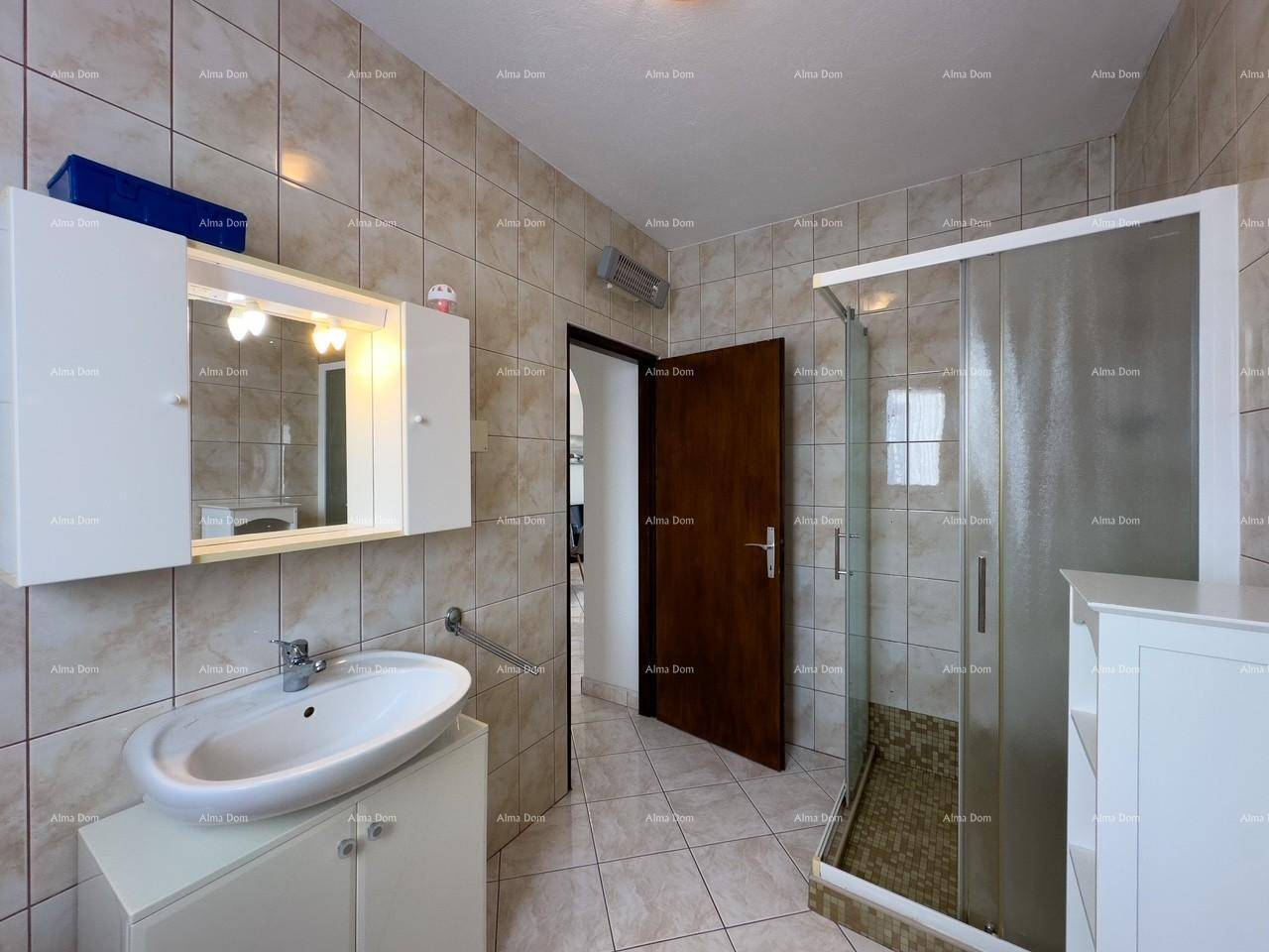 Badezimmer mit Duschkabine, Waschbecken und Spiegelschrank, durch eine Tür zugänglich.
