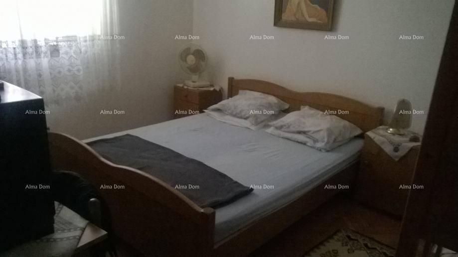 Schlafzimmer mit Holzbett, Nachttisch und einem Ventilator für angenehme Kühlung.