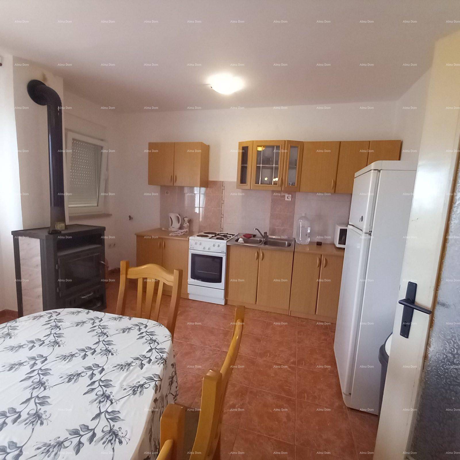 Küche mit hellen Holzschränken, Herd und Kühlschrank, kombiniert mit einem Esstisch.