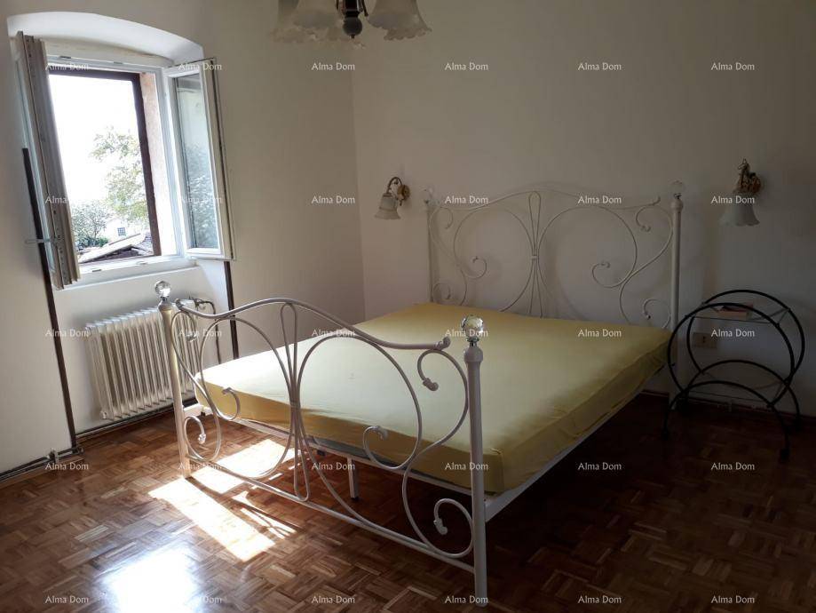 Schlafzimmer mit einem dekorativen weißen Metallbettgestell und Parkettboden.