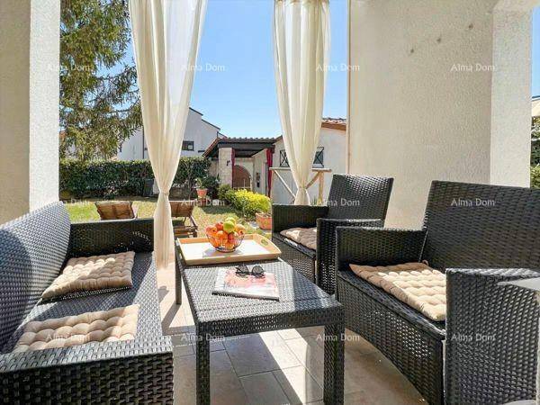 Gemütliche Terrasse mit Rattanmöbeln, Vorhängen und Blick auf den gepflegten Garten.