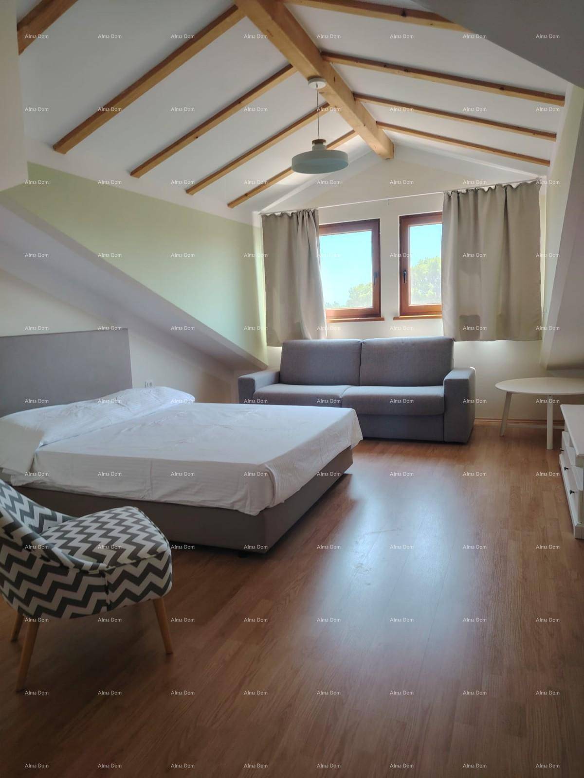 Helles Schlafzimmer im Dachgeschoss mit Holzbalken, Doppelbett und Sofa, bietet eine gemütliche Atmosphäre.