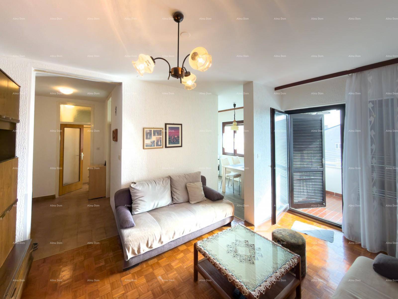 Gemütliches Wohnzimmer mit Parkettboden, Sofa und Zugang zu einem Balkon.