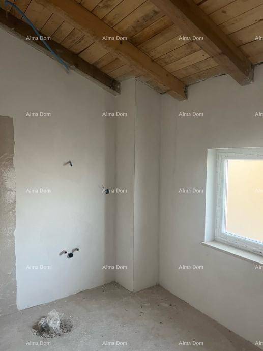Unfertiger Innenraum mit Holzbalkendecke, weiß verputzten Wänden und einem Fenster.