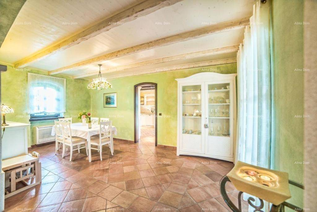 Helles Esszimmer mit grün gestrichenen Wänden, Terrakottaboden und einem weißen Vitrinenschrank.