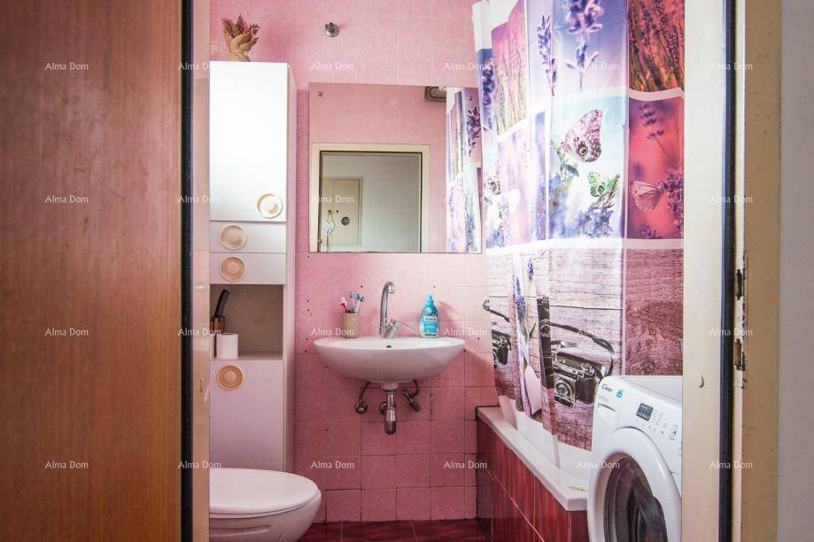 Badezimmer mit rosa Fliesen, Waschbecken, Toilette und Waschmaschine.
