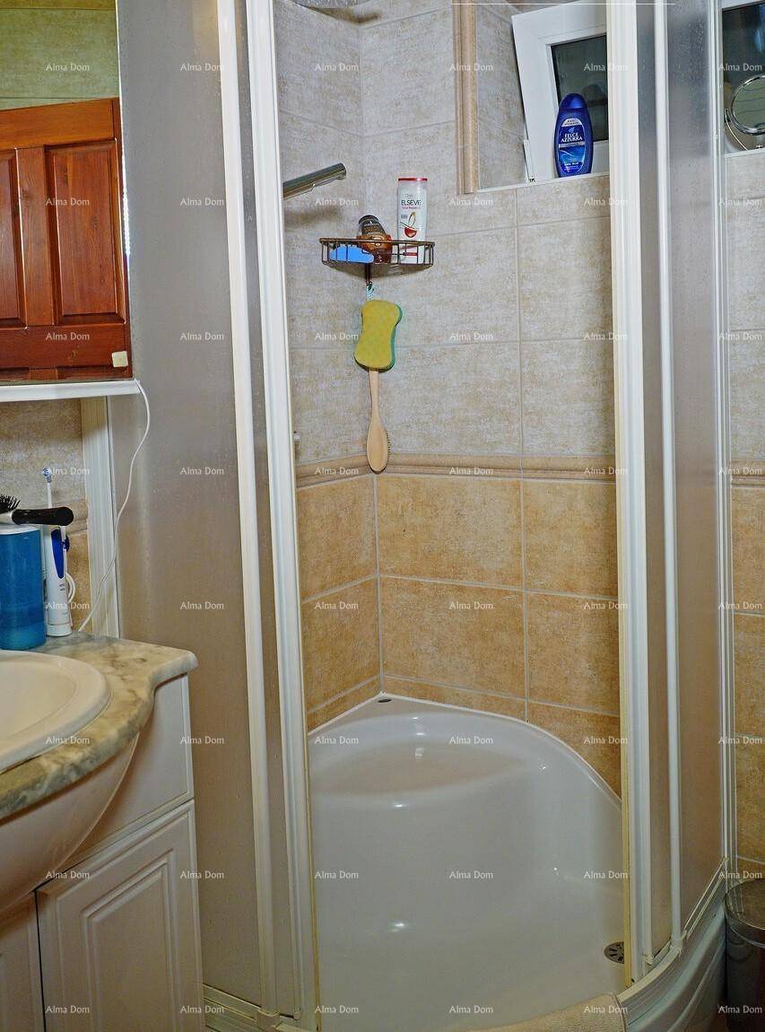Badezimmer mit Eckduschkabine und Waschbecken, ausgestattet mit hellen Fliesen.