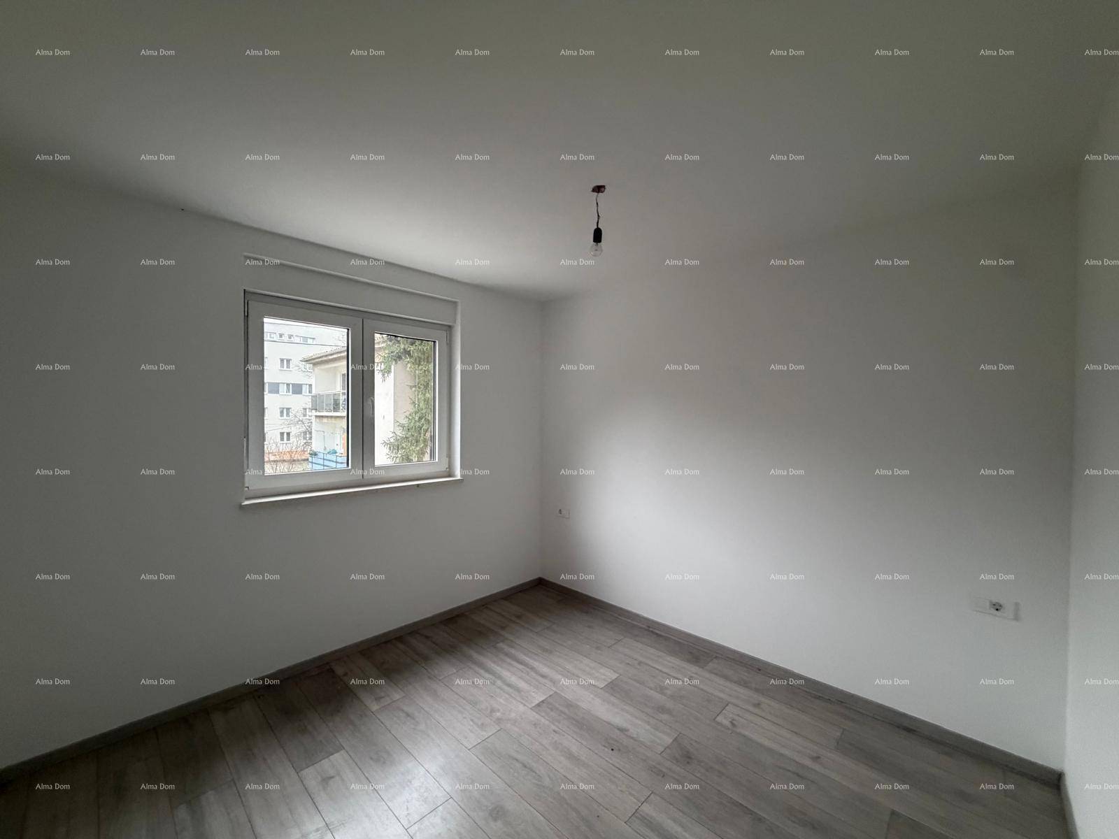 Helles Schlafzimmer im Rohbau mit Laminatboden und einem Fenster.