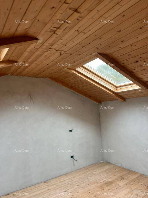 Dachgeschossraum im Rohbau mit Holzdielenboden, Holzbalkendecke und einem Dachfenster für Tageslicht.