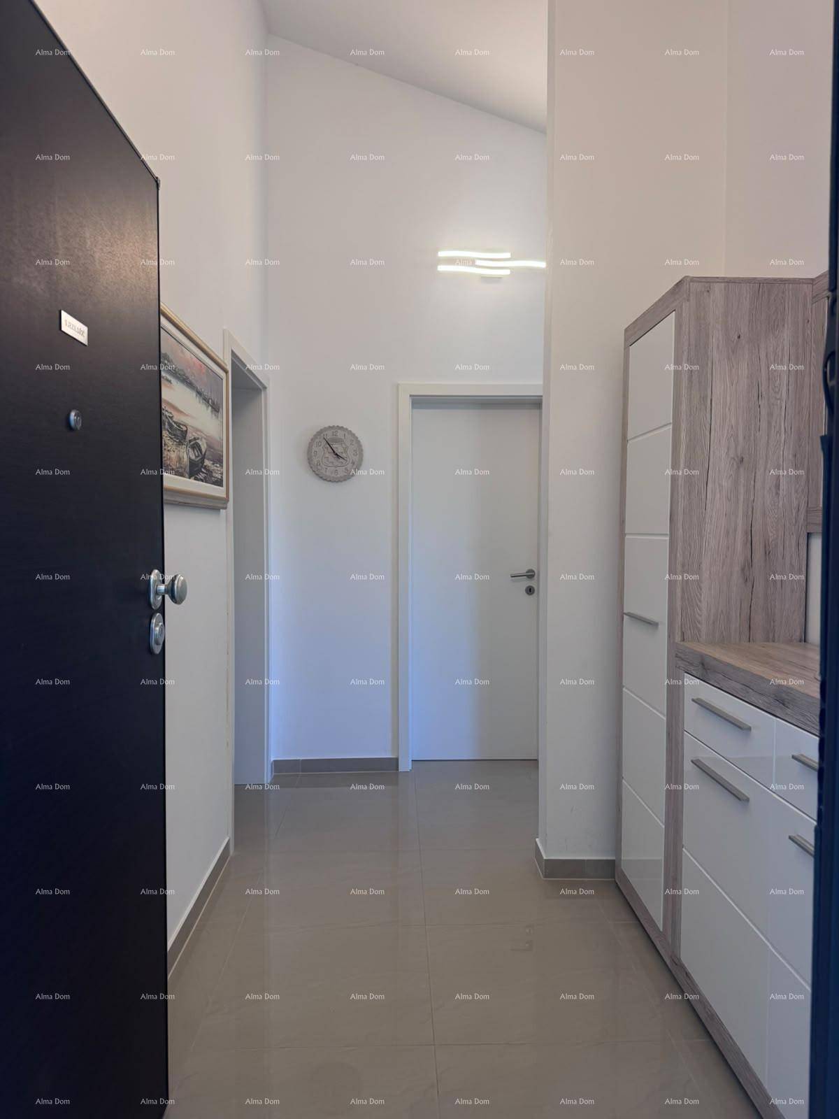 Heller Flur mit modernen Fliesen, einem Holzschrank und Zugang zu weiteren Räumen.