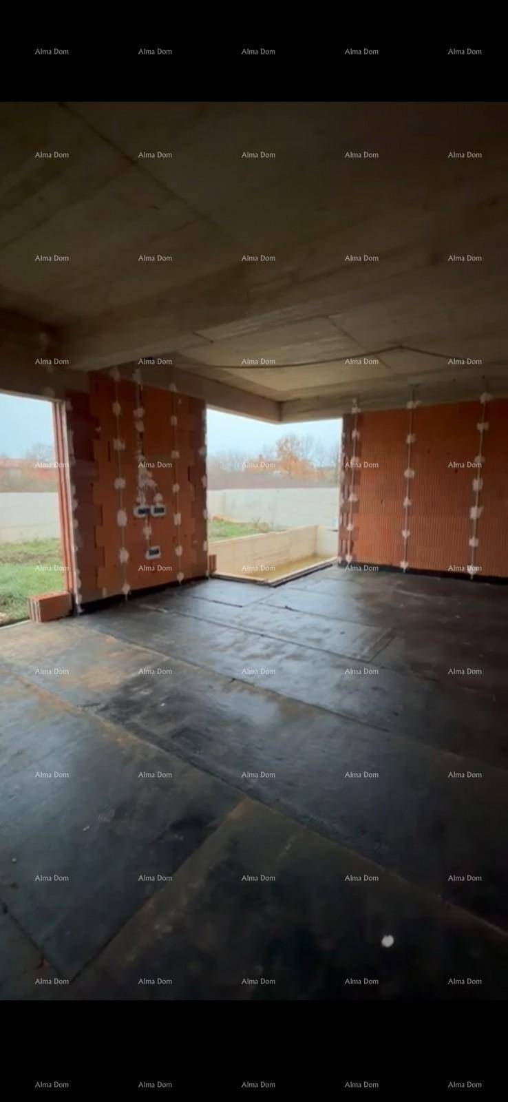 Innenraum im Rohbau mit unverputzten Ziegelwänden, Betonboden und großen Fensteröffnungen.